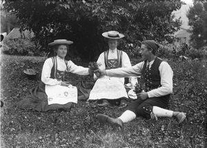 A man and two women sitting on the grass, circa 1910